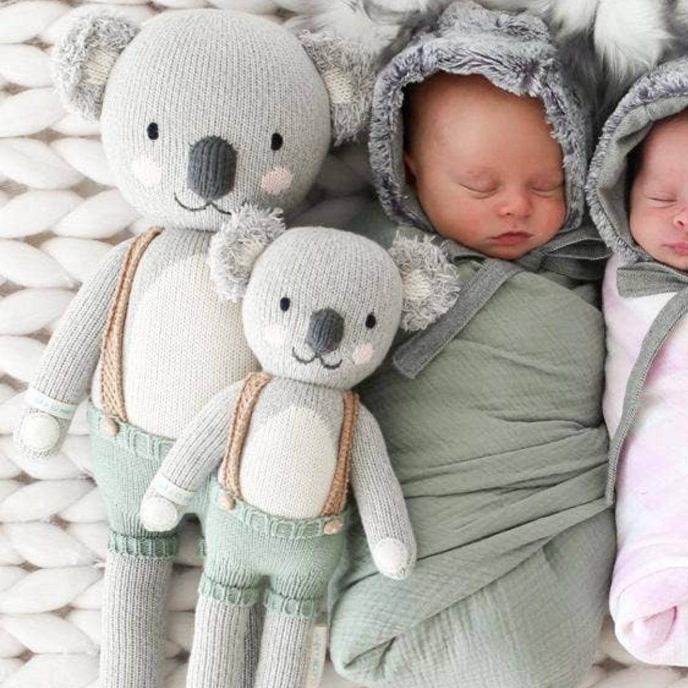 
                      
                        Both sizes of Quinn the Koala placed next to two sweet, swaddled babies, demonstrating Quinn's versatility as a gift for newborns and children.
                      
                    