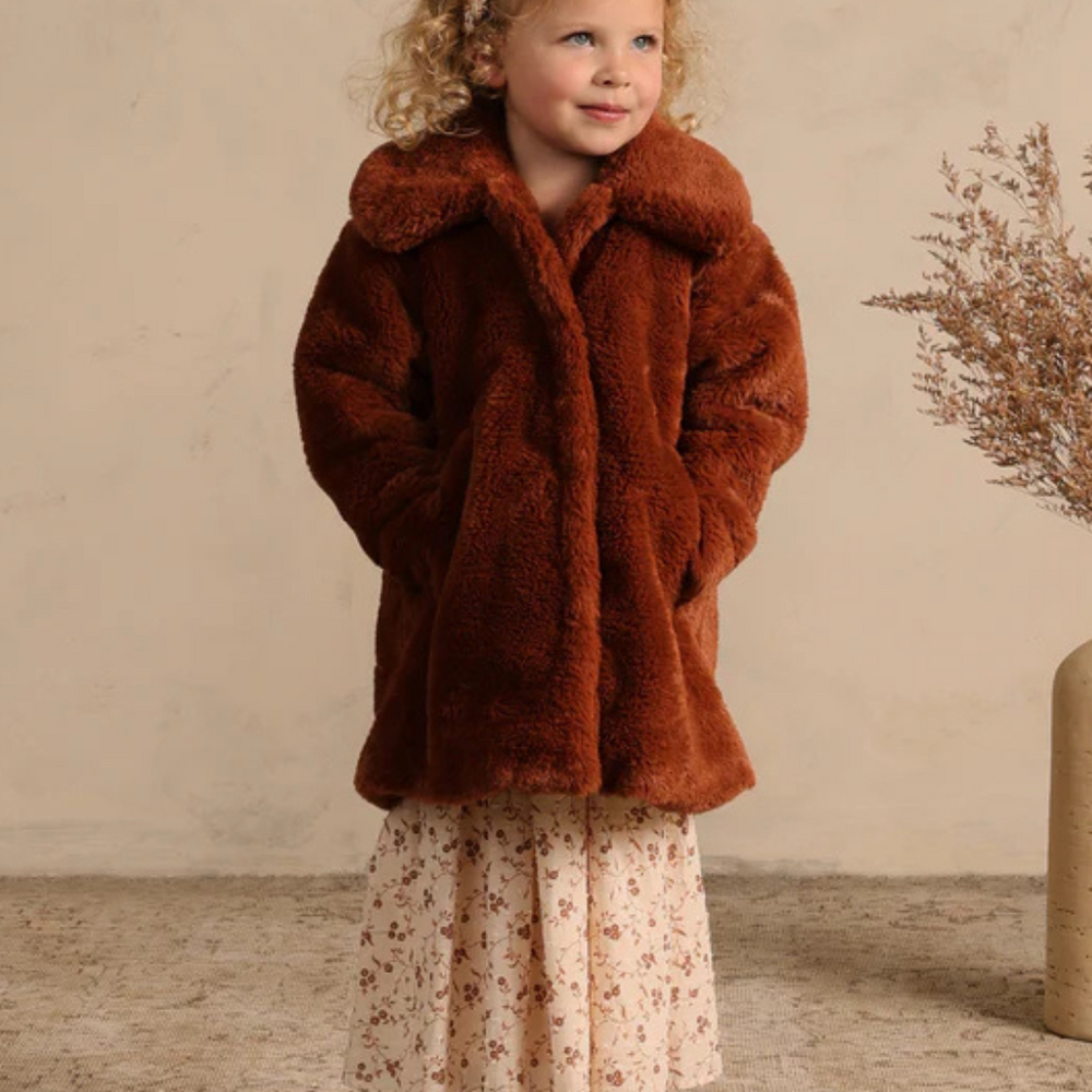 Full view of Eloise Coat in Copper on model, a trendy faux fur coat for kids with practical front pockets and hidden snaps.