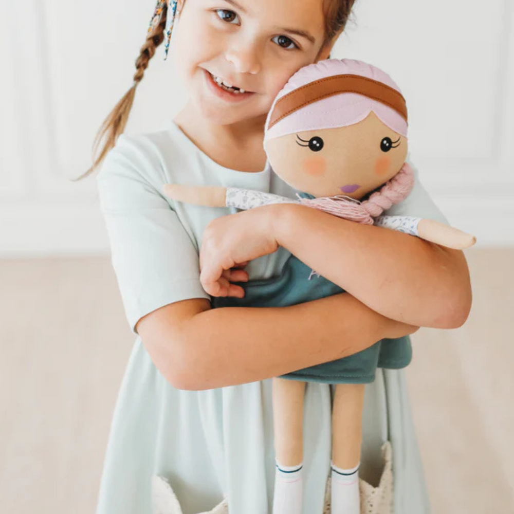 Little girl hugging her Fair Kindness Doll, showcasing the doll’s comforting design and positive message of kindness.