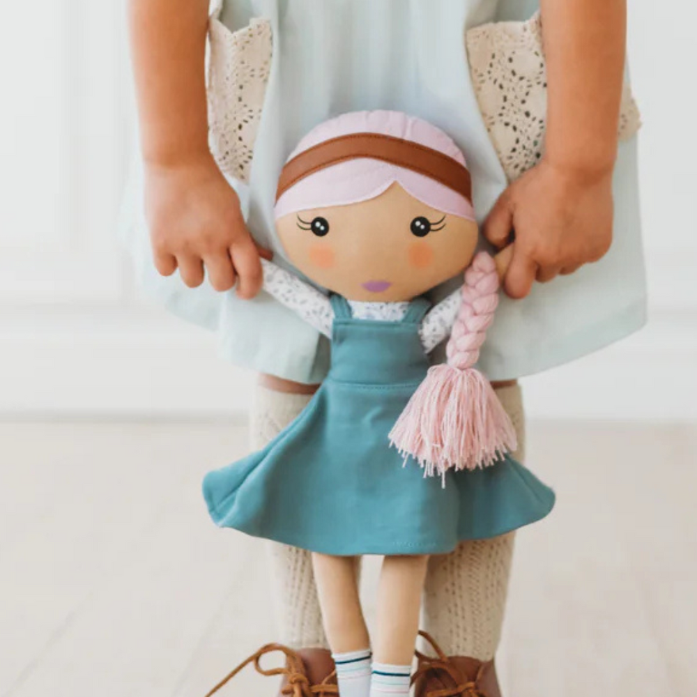 Close-up of the Fair Kindness Doll being held by a child, emphasizing its 18-inch size and soft features.