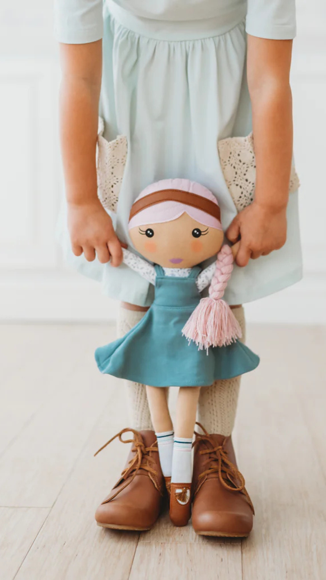 Close-up of the Fair Kindness Doll being held by a child, emphasizing its 18-inch size and soft features.