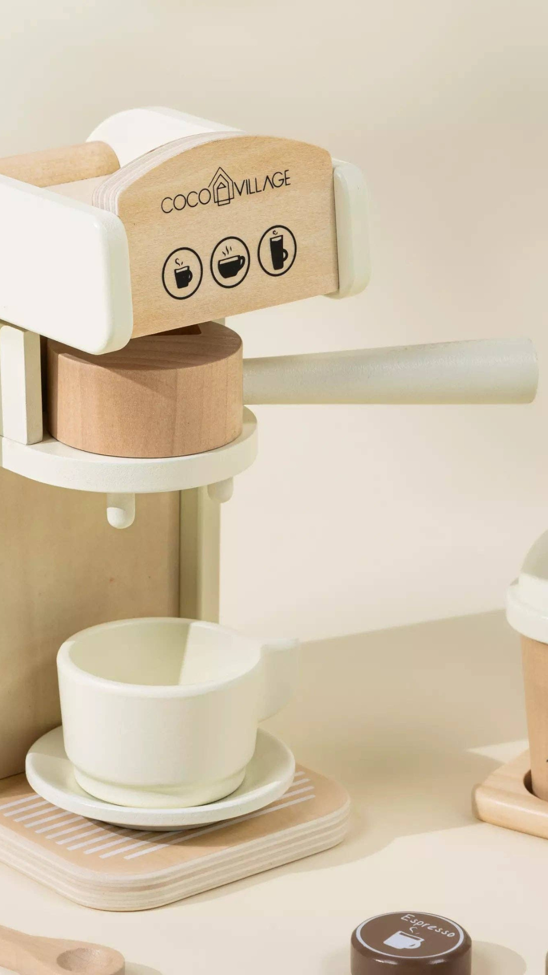 Close-up of Wooden Coffee Maker Set with a coffee cup placed on the machine, surrounded by coffee pods, spoon, and accessories, perfect for imaginative pretend play and fostering social skills.