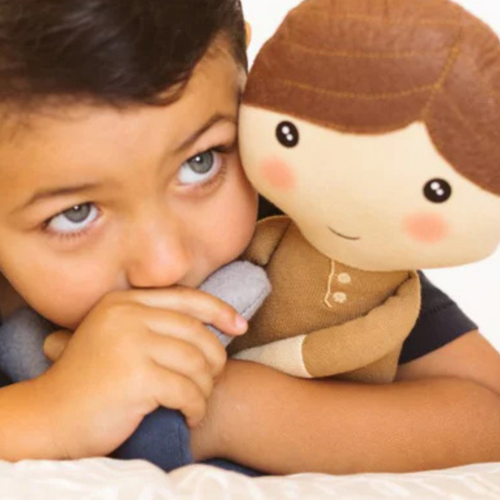 Smiling boy cuddling the soft and huggable Hope Kindness Doll, spreading kindness and love.