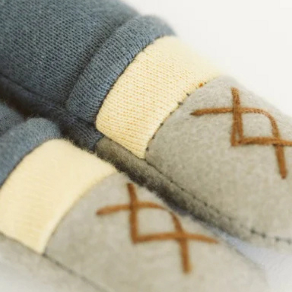 
                      
                        Detailed view of the Hope Kindness Doll's cozy gray felt shoes, denim pants, and camel-hued henley top.
                      
                    