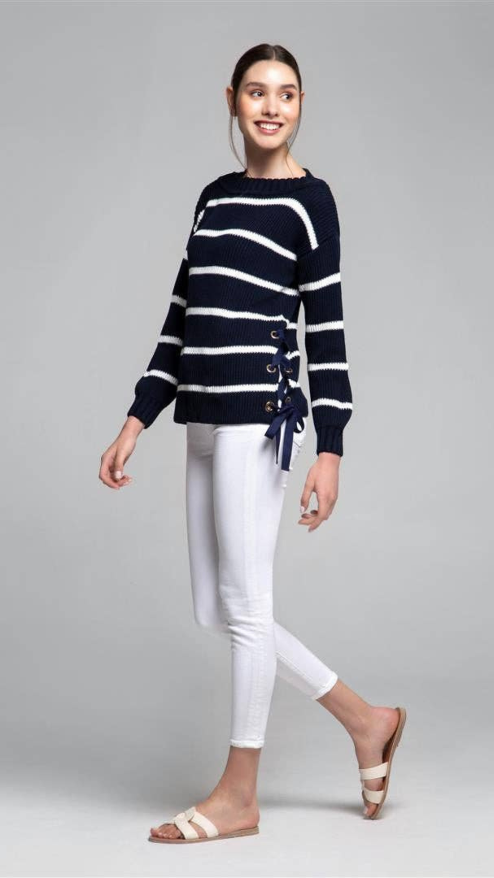 Model wearing Monaco Sweater in midnight blue and white with side slit and gold metal eyelets