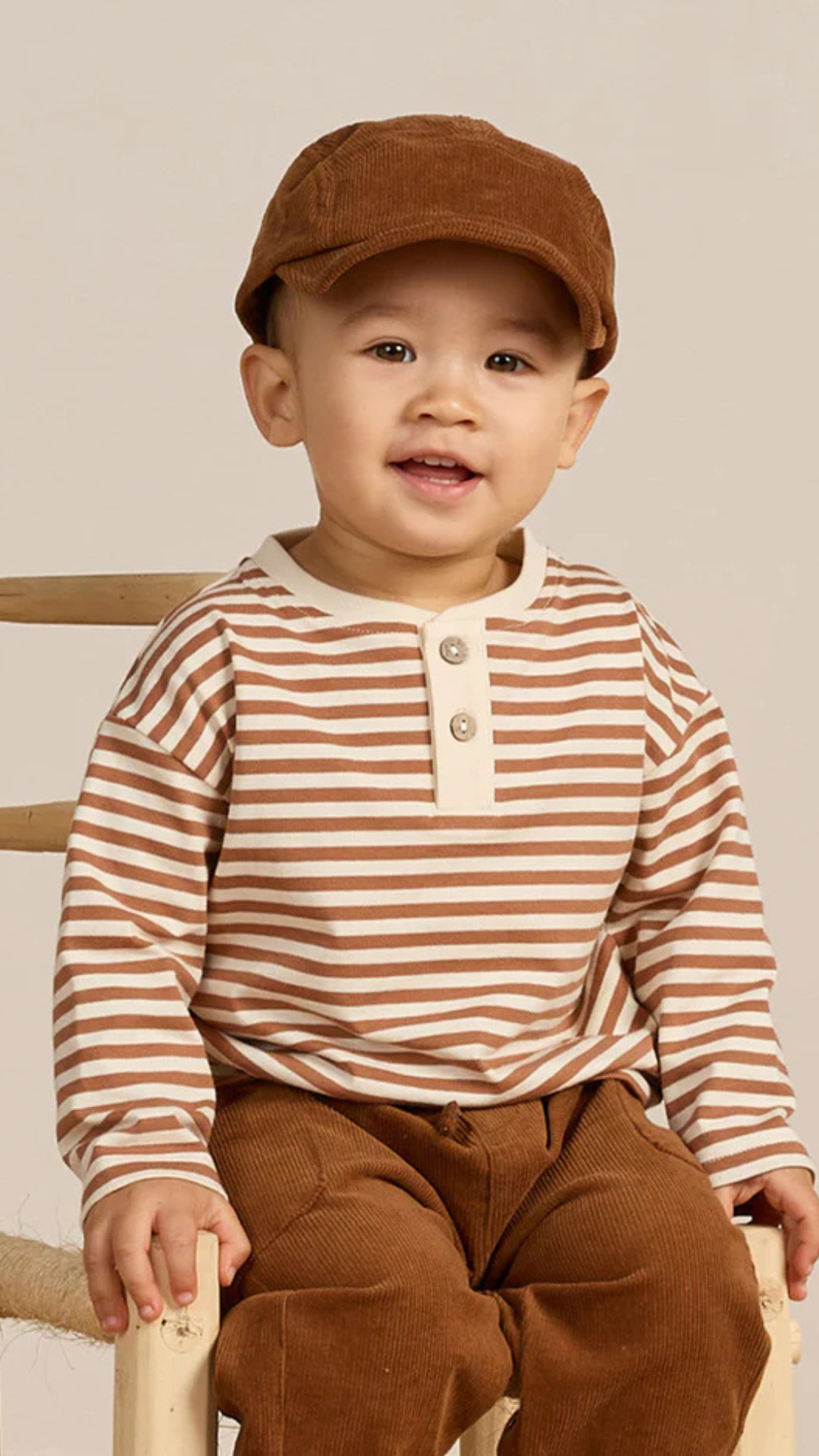 Toddler model wearing cinnamon stripe Henley Tee with matching corduroy cap by Quincy Mae, ideal for fall outings.