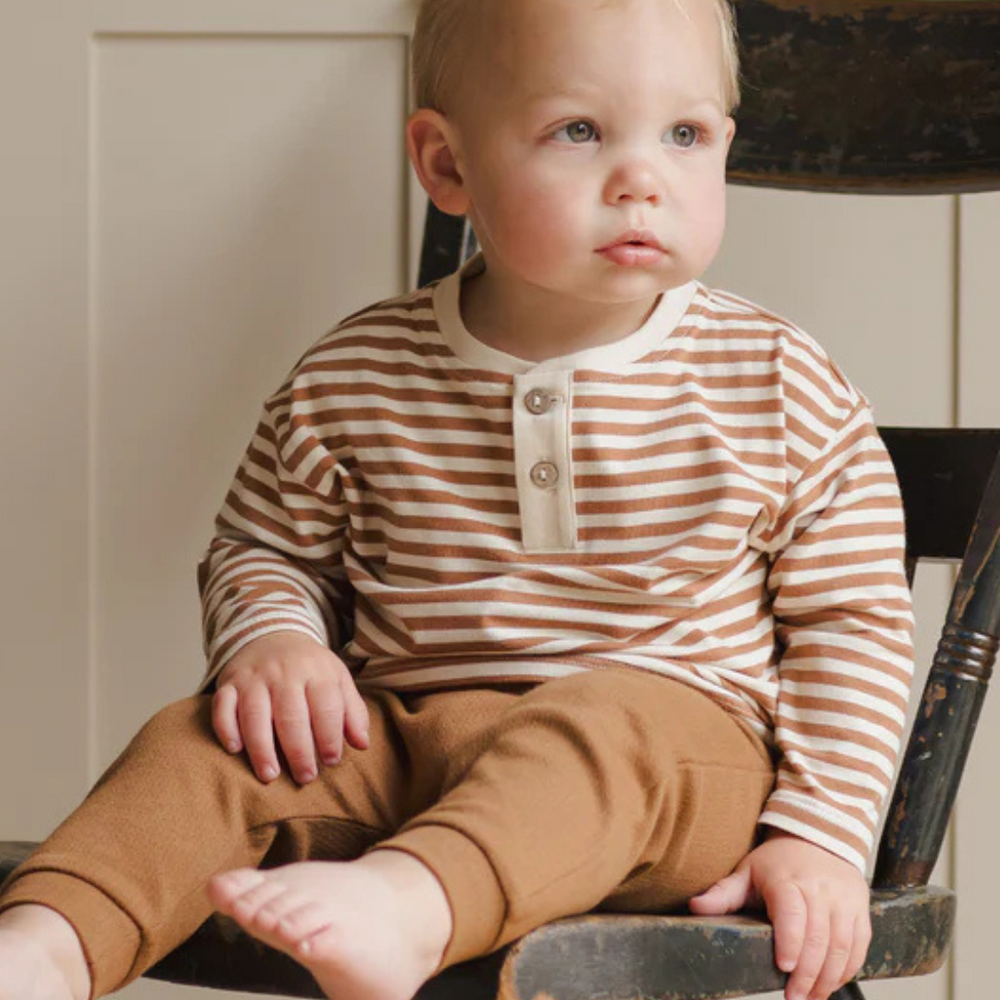 Close-up of toddler in soft organic Henley Tee, featuring cinnamon stripes and light coconut buttons.