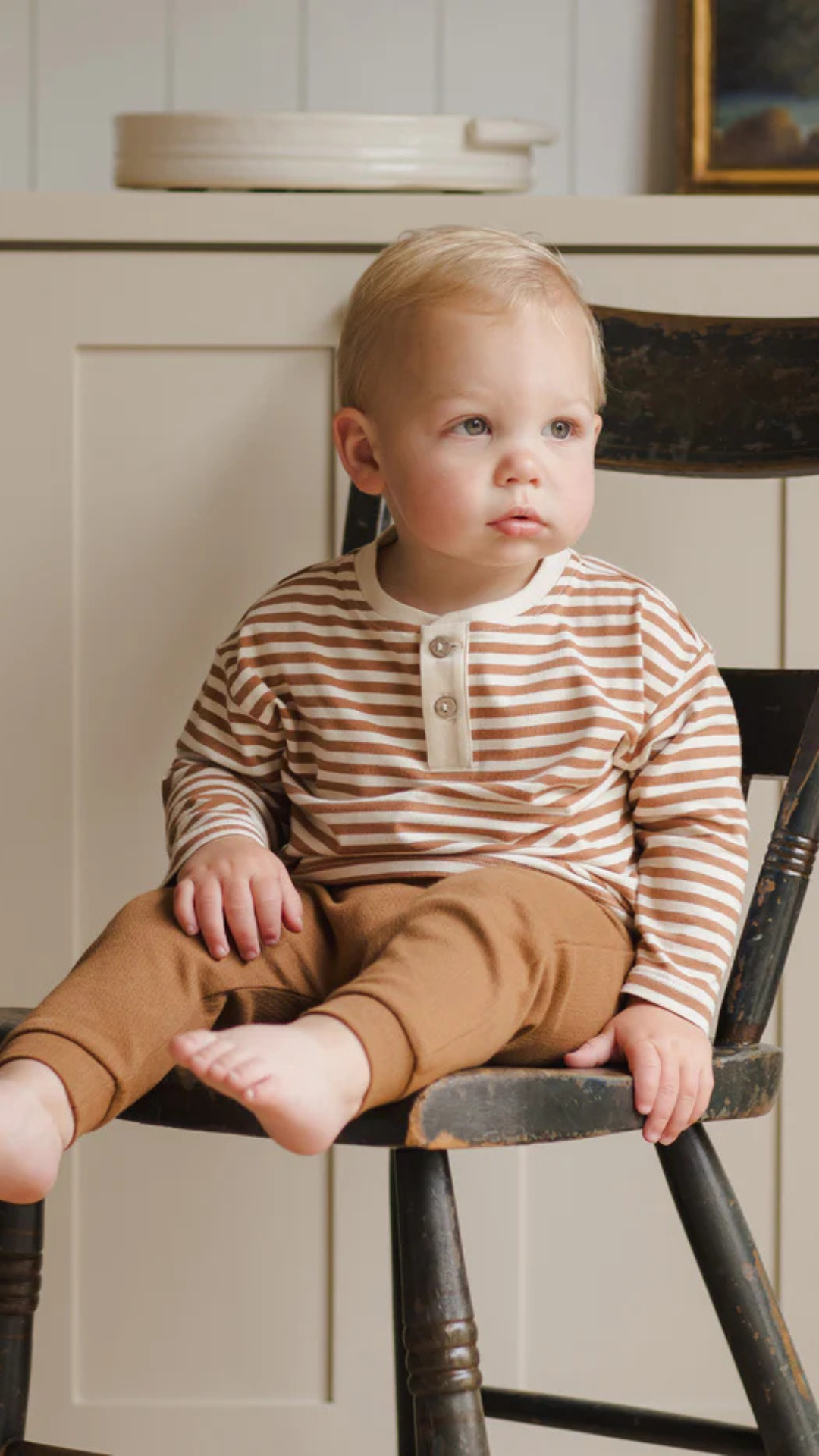 Close-up of toddler in soft organic Henley Tee, featuring cinnamon stripes and light coconut buttons.