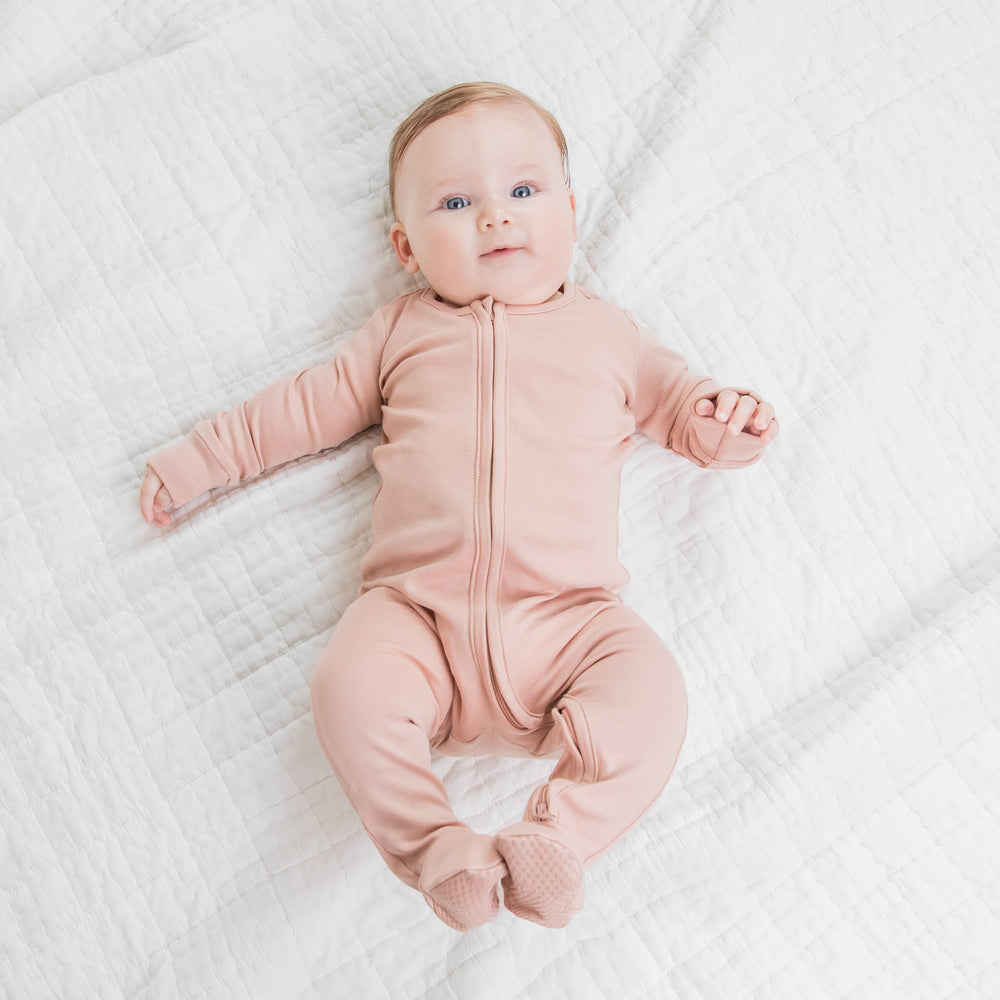 A sweet baby lying down in the Colored Organics Organic Cotton Zipper Footed Sleeper, captured from above, showcasing the soft fabric and cozy fit.
