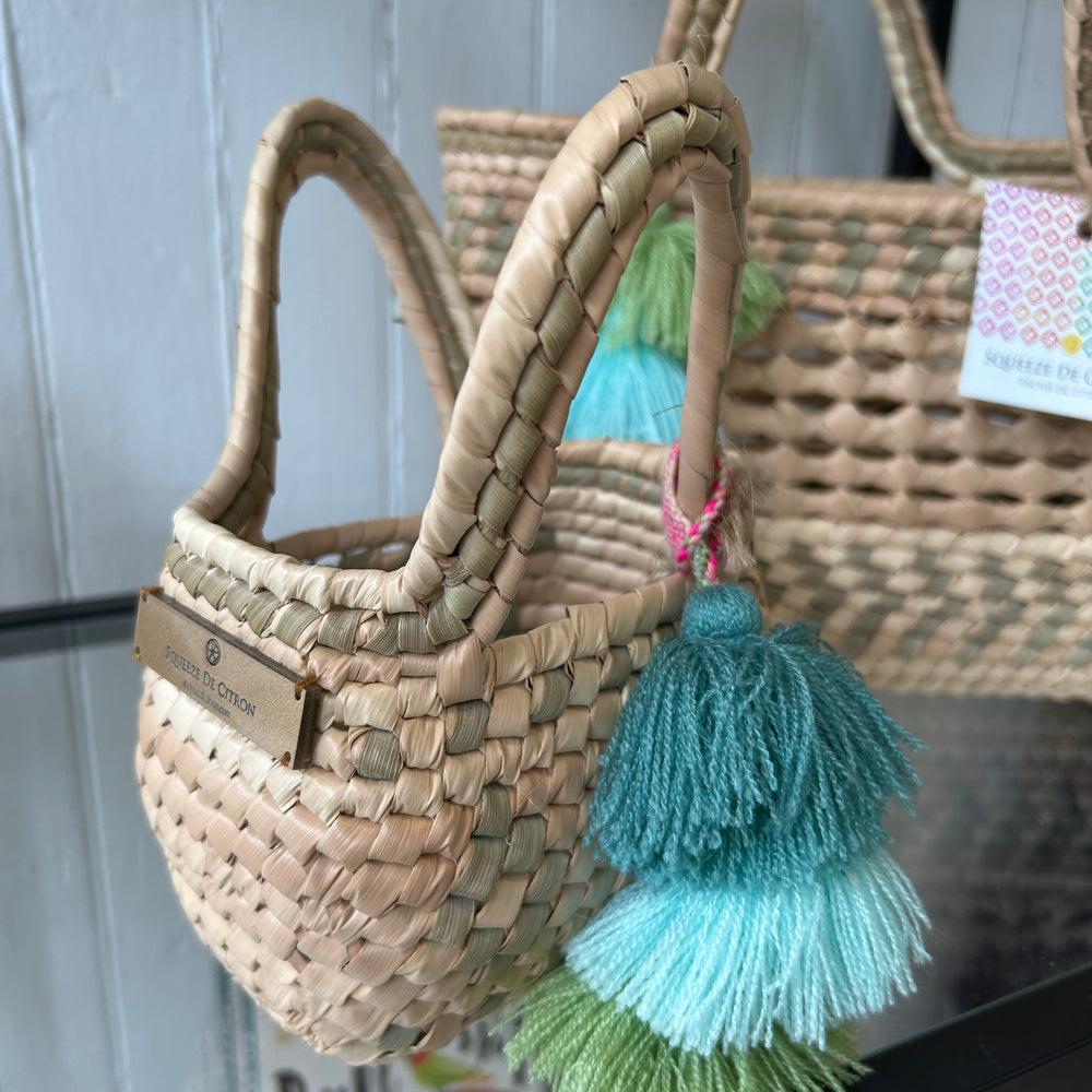 
                      
                        Close-up of the Palm Net Yatzil Mini Tote in Sage on a shelf, highlighting the sustainable palm leaf material, detailed weaving, and versatile carrying handles.
                      
                    