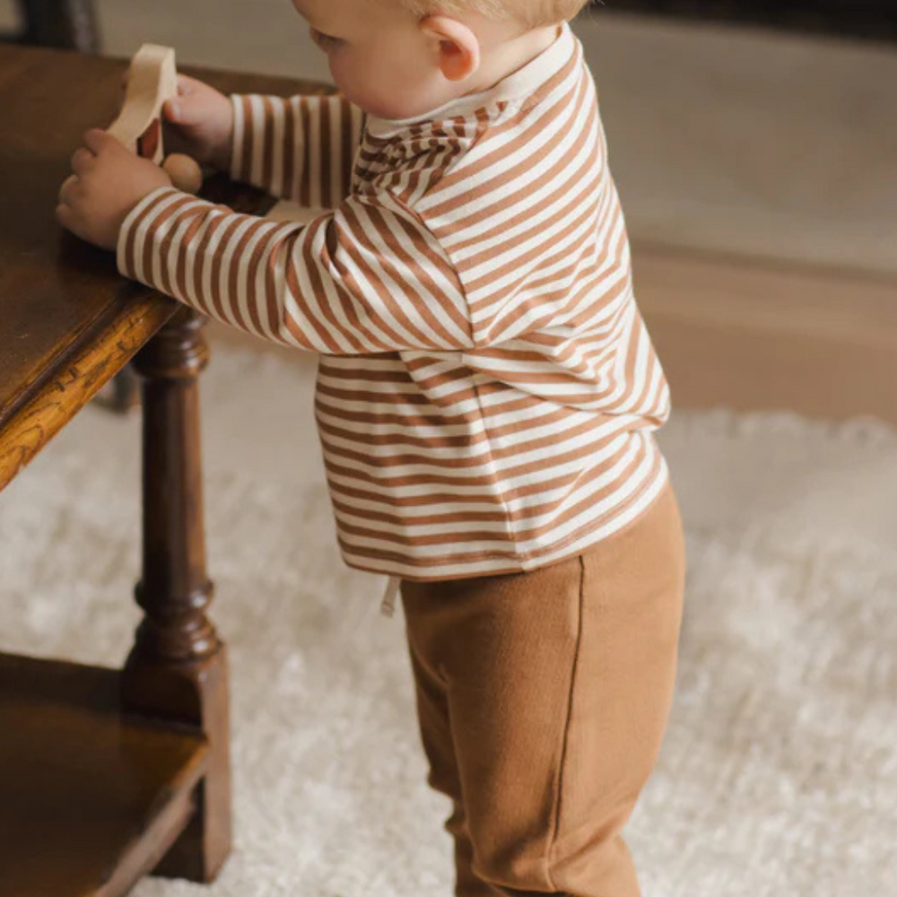 
                      
                        Toddler boy playing in cozy Long Sleeve Henley Tee with organic cotton cinnamon stripe design.
                      
                    