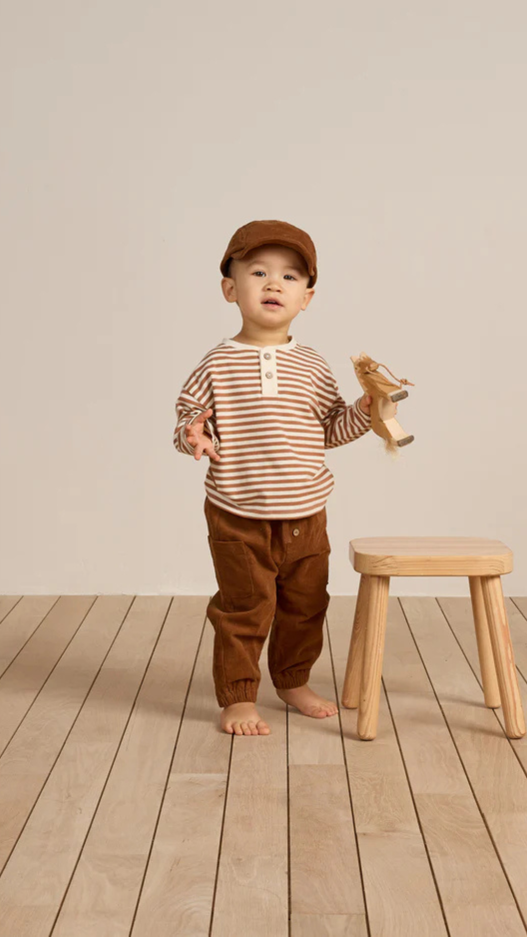 Model wearing the Corduroy Baby Cap in cinnamon, completing a cozy, sustainable baby outfit.