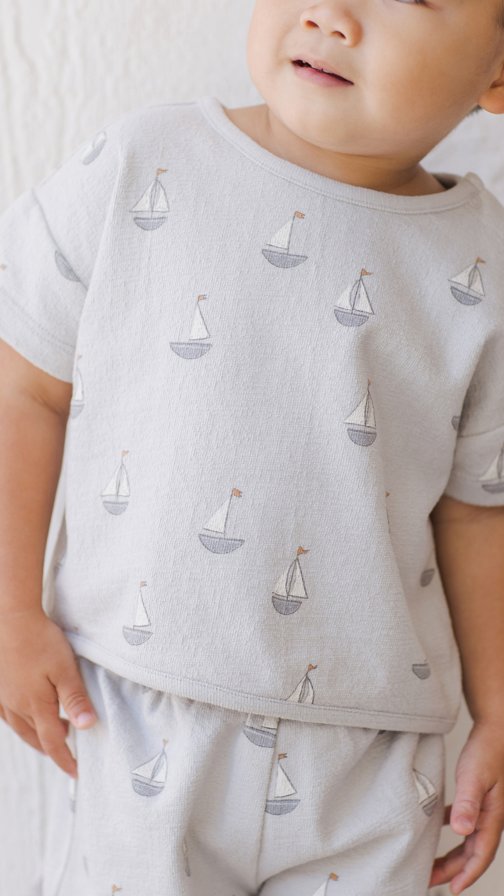 A detailed close-up of a toddler boy wearing the Spongy Play Set - Sailboats by Quincy Mae, showcasing the ultra-soft, breathable fabric and charming nautical sailboat print.