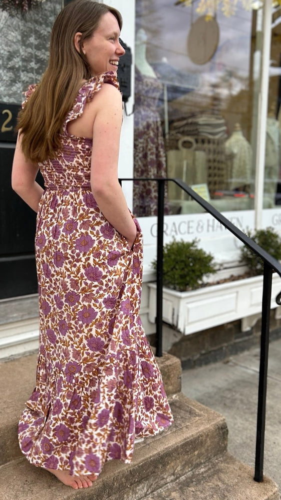 Side view of my sister wearing the Sasco Dress in Lilac Orsay Floral by Marea outside our shop in Essex, CT – showcasing the flattering smocked bodice and flowy silhouette, perfect for spring occasions.
