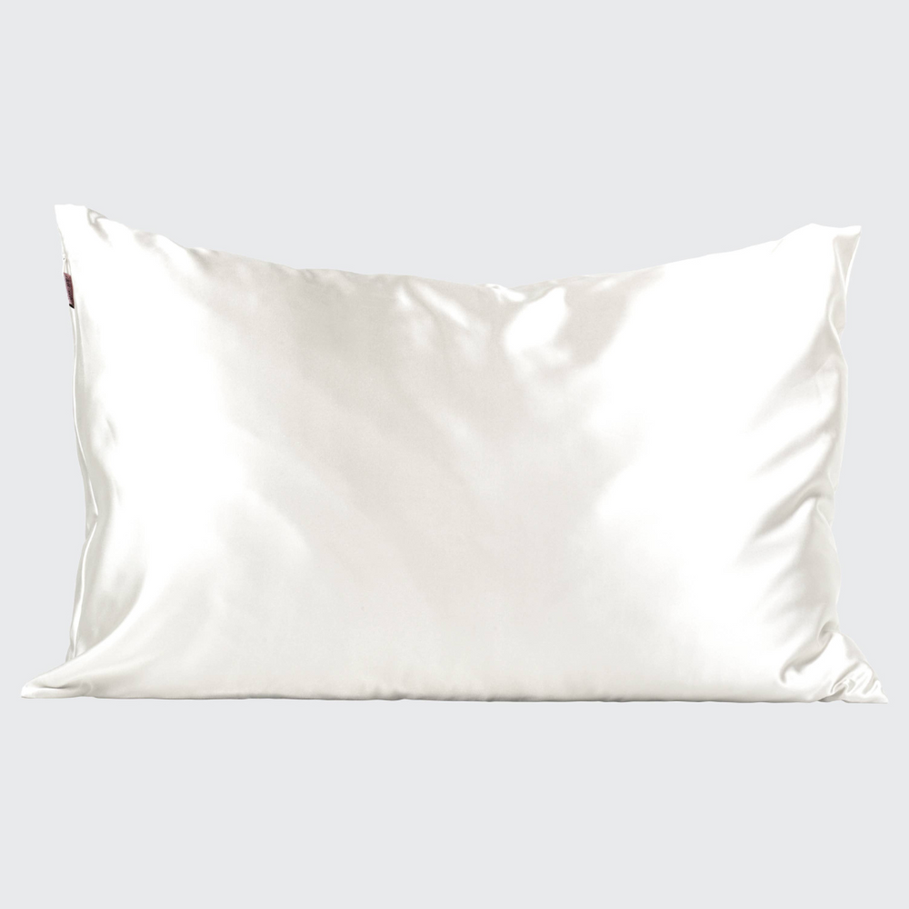 A neatly laid-out Satin Pillowcase in Ivory by Kitsch, highlighting the soft, shiny satin fabric against a plain background.