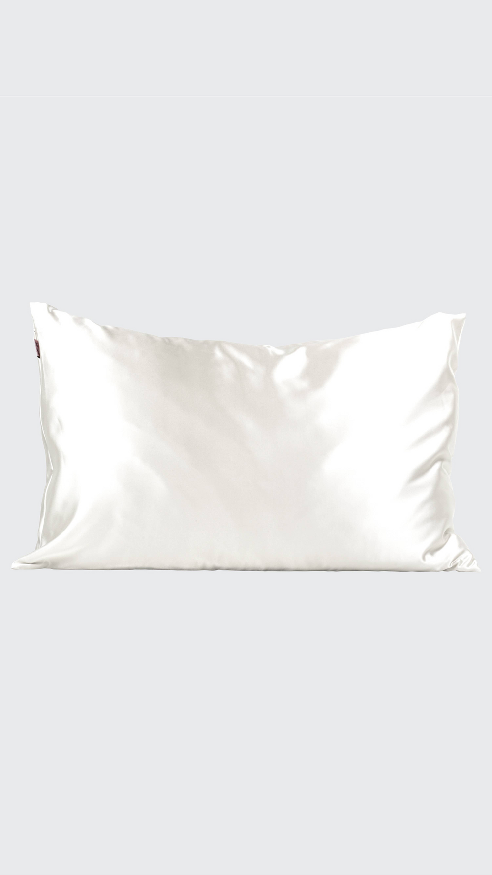 A neatly laid-out Satin Pillowcase in Ivory by Kitsch, highlighting the soft, shiny satin fabric against a plain background.