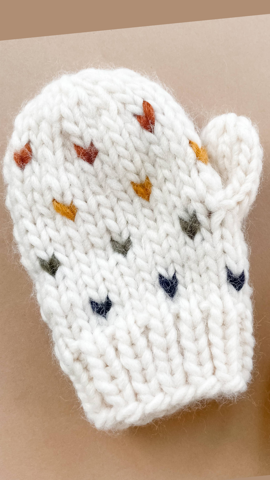 A detailed close-up view of the Sawyer Heart Mittens by Blueberry Hill, showcasing the soft hand-knit texture and charming heart design in pastel hues.