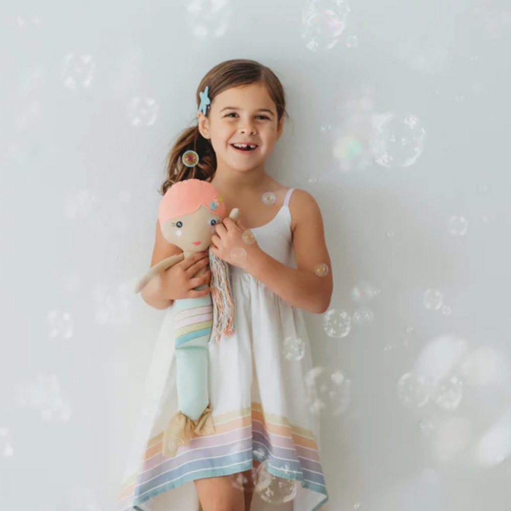 
                      
                        Smiling child holding the Shine Mermaid Kindness Doll, radiating joy as she bonds with her kindness companion.
                      
                    