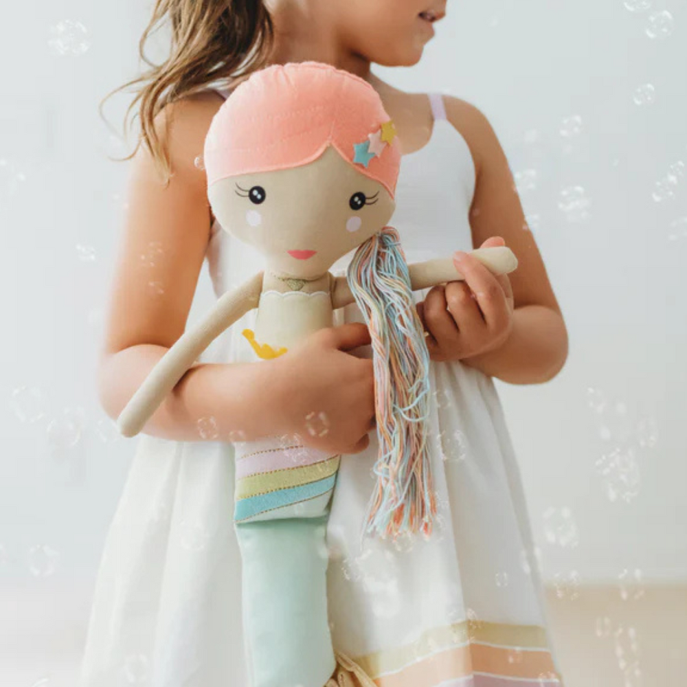 
                      
                        A tender moment of a child holding her Shine Mermaid Kindness Doll, emphasizing the emotional connection and joy the doll brings while teaching kindness.
                      
                    