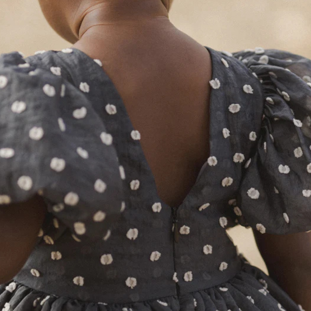 
                      
                        Close-up of the back of the Sophia Dress by Noralee, showcasing the delicate polka dot pattern and soft, breathable fabric, perfect for special occasions.
                      
                    