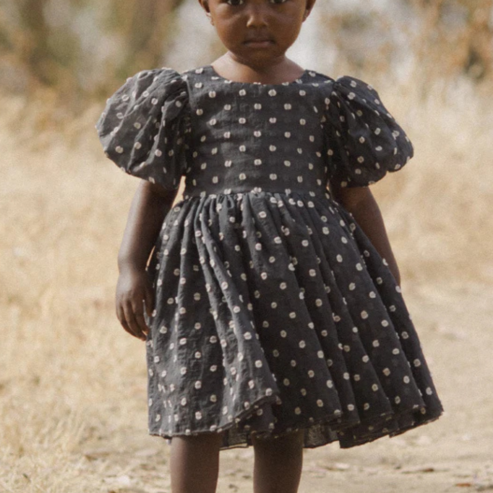 
                      
                        Front view of a model in a field wearing the Sophia Dress, paired with matching shoes, emphasizing the timeless style and versatility for outdoor events.
                      
                    