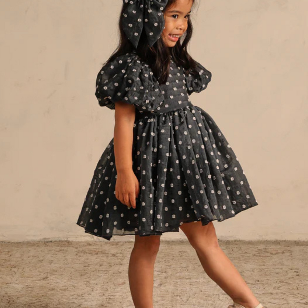 Playful model wearing the Sophia Dress in a studio, capturing the dress’s whimsical charm and comfortable fit as she twirls with joy.