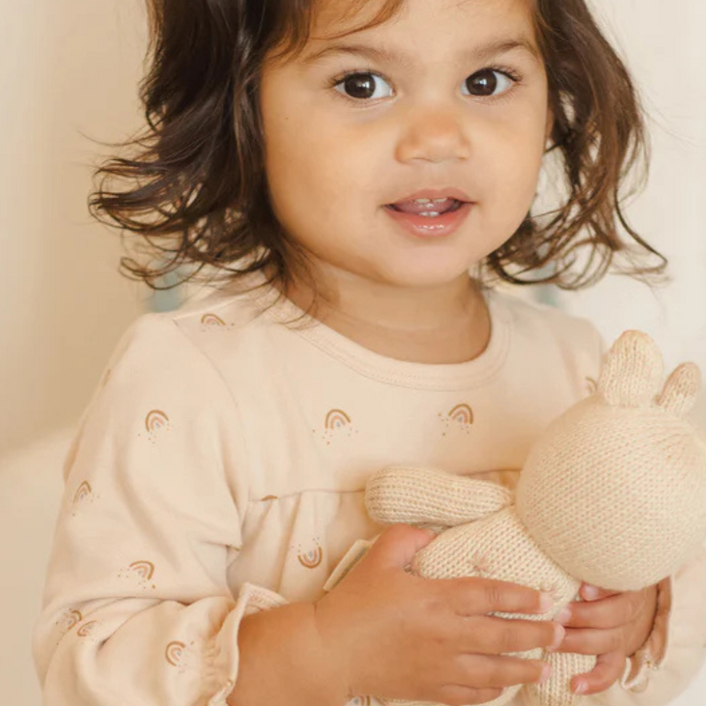 Close-up of Quincy Mae Tiered Jersey Dress in Rainbows on toddler, detailing the soft shell-colored jersey fabric with rainbow print and tiered design for comfort and charm.