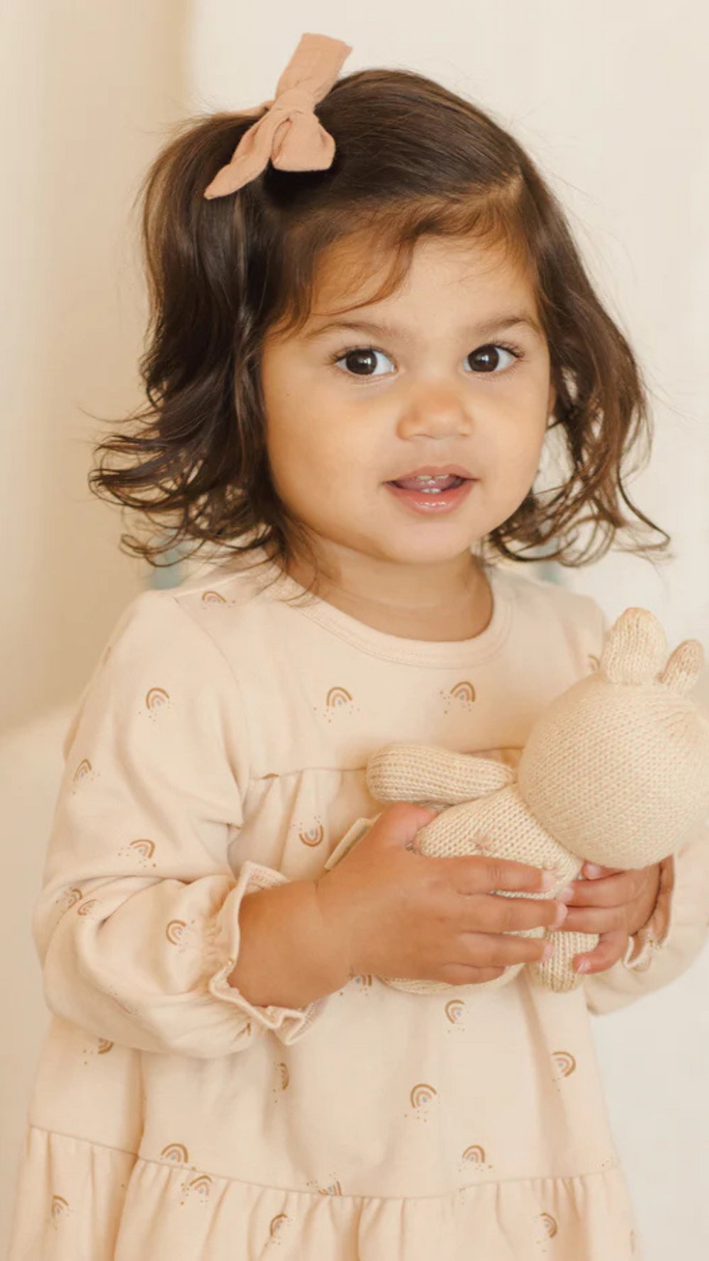 Close-up of Quincy Mae Tiered Jersey Dress in Rainbows on toddler, detailing the soft shell-colored jersey fabric with rainbow print and tiered design for comfort and charm.