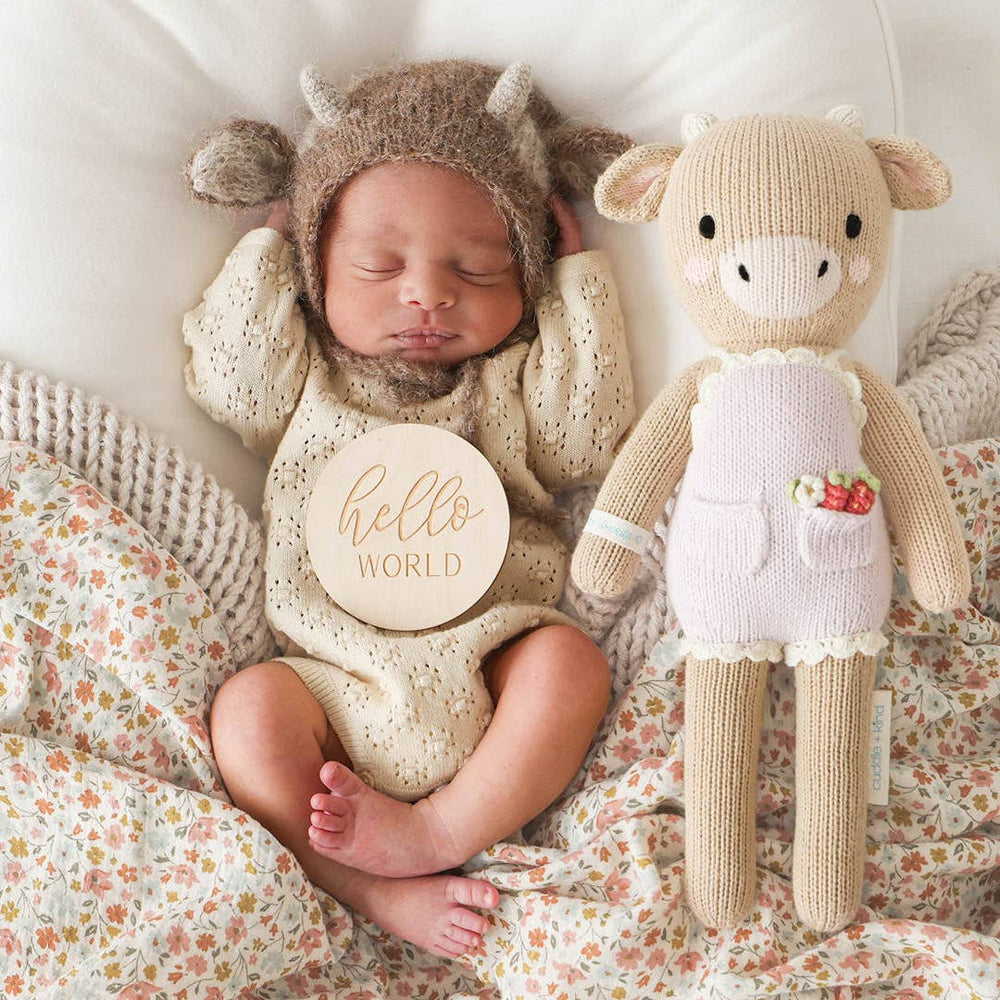 
                      
                        Ava the Cow hand-knit doll cuddled next to a newborn baby, highlighting size and softness as a perfect gift for infants
                      
                    
