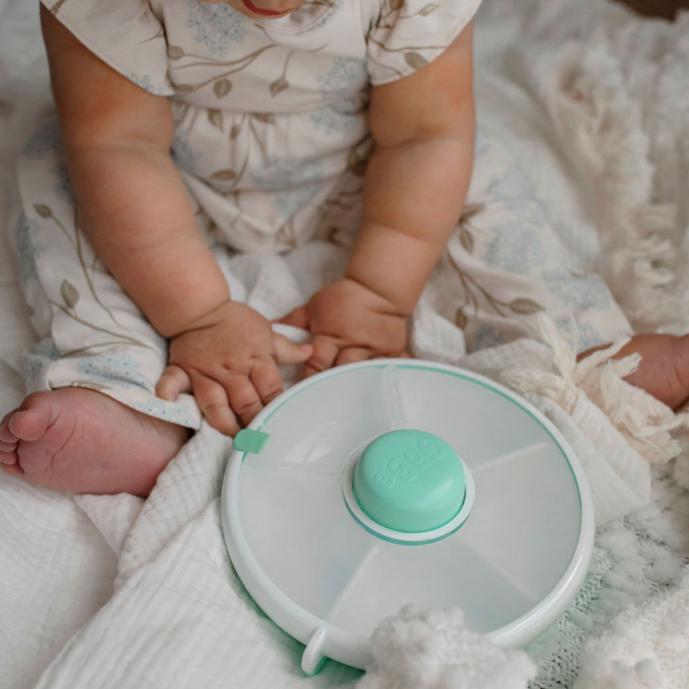 Close-up of a baby holding a 5-compartment snack spinner, perfect for toddlers to easily grab and enjoy a variety of snacks.