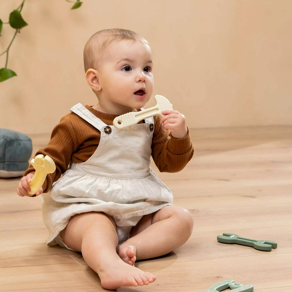 
                      
                        Baby holding and playing with a silicone tool from the 4-piece set, supporting motor skills and teething comfort
                      
                    