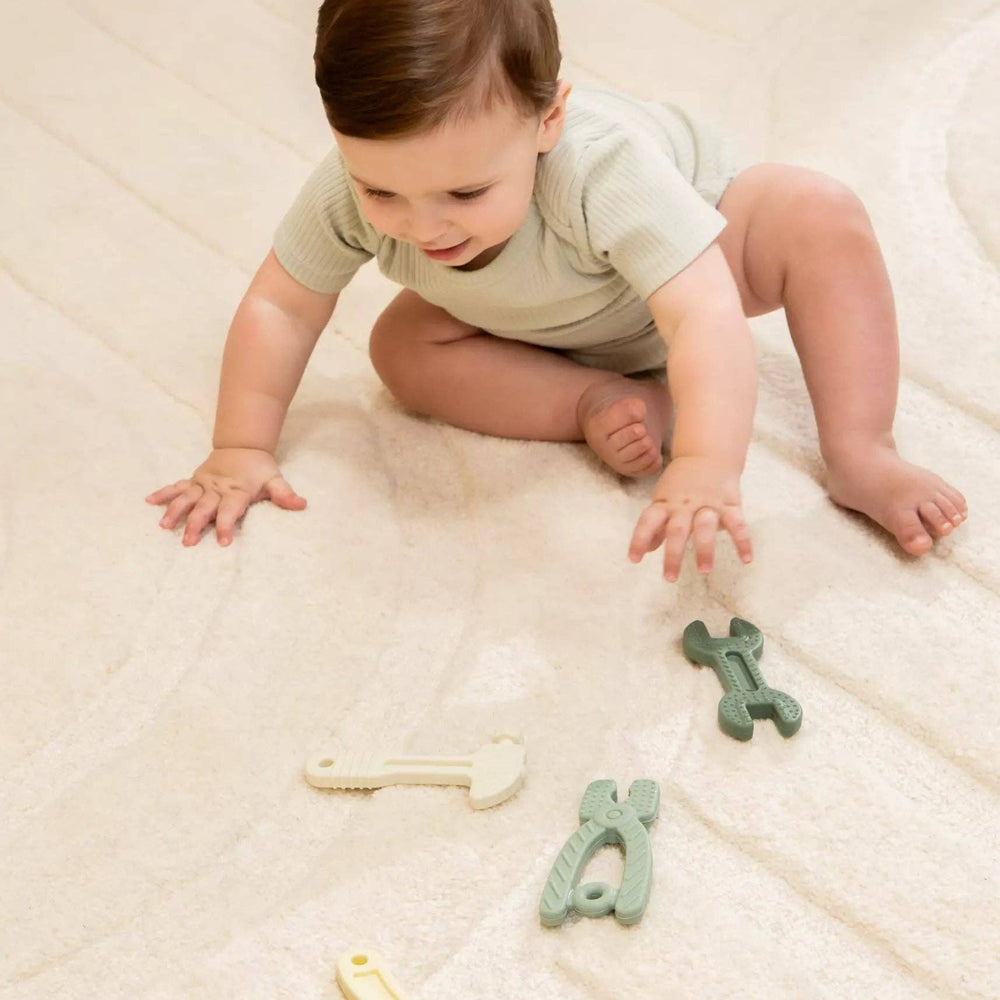 
                      
                        Baby holding and playing with a silicone tool from the 4-piece set, supporting motor skills and teething comfort
                      
                    