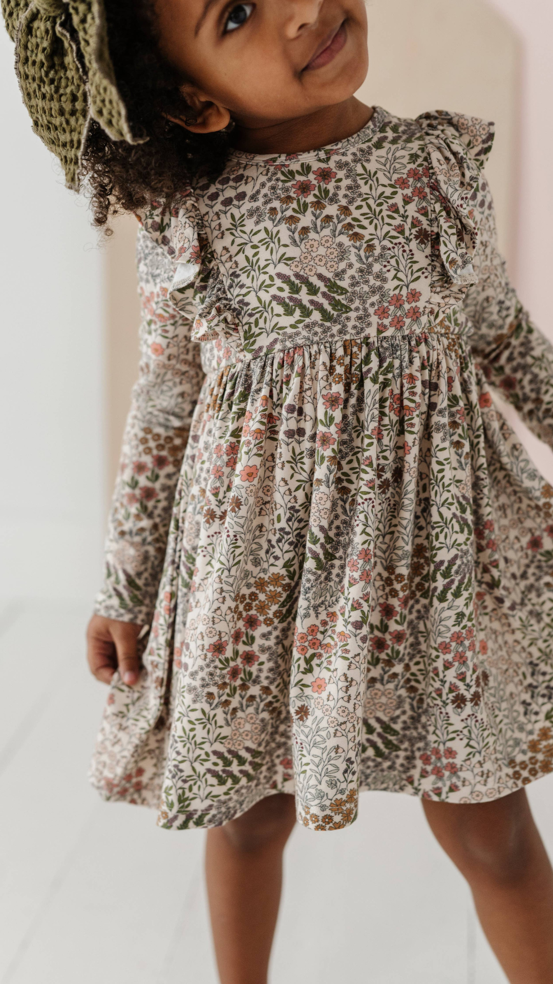 Front view of toddler in Baby & Toddler Ruffle Dress in Winter Floral, showcasing soft bamboo jersey fabric and festive floral print, perfect for fall.