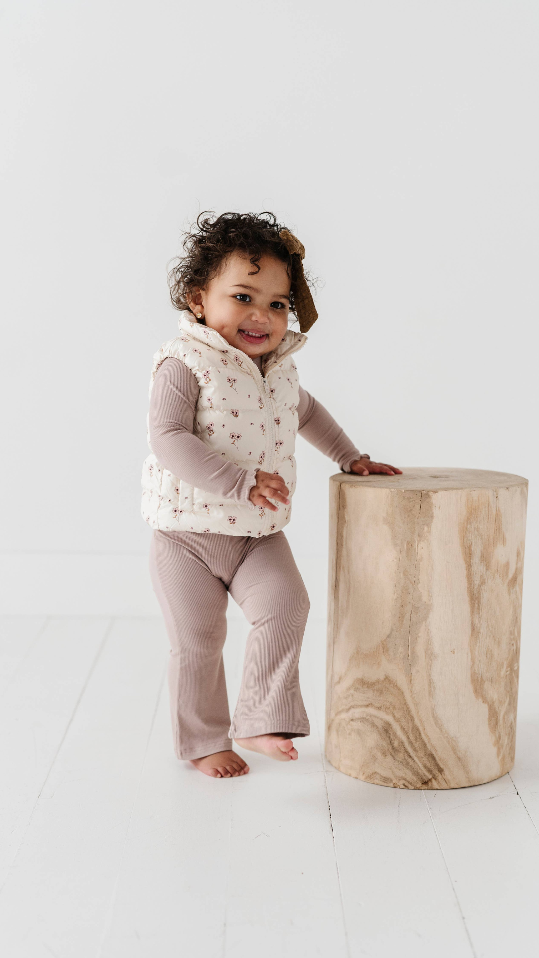 Full view of little girl in Ditsy Floral Puffer Vest, showing off the floral pattern and comfortable fit for outdoor adventures and playdates.