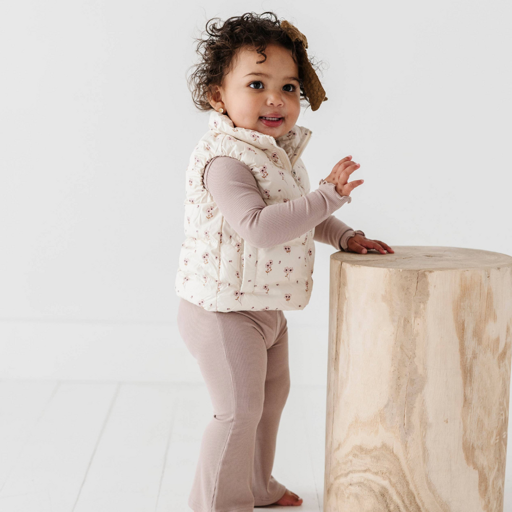 
                      
                        Toddler side view in Ditsy Floral Puffer Vest in studio, showcasing the cozy fit and playful design ideal for chilly days and outdoor activities.
                      
                    