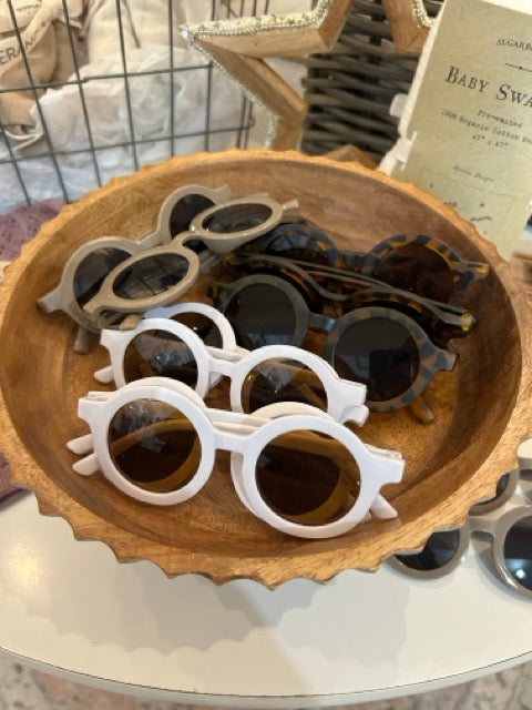 Baby and toddler round sunglasses flatlay showing lightweight UV protective kids sunglasses in neutral colors, the perfect match for any outfit.