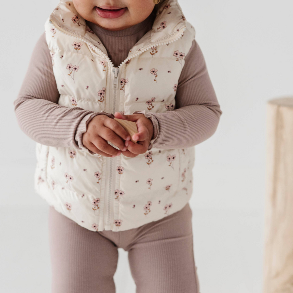 
                      
                        Toddler playing in the studio, ready for outdoors in Ditsy Floral Puffer Vest, combining warmth and style for fun winter adventures and active playdates.
                      
                    