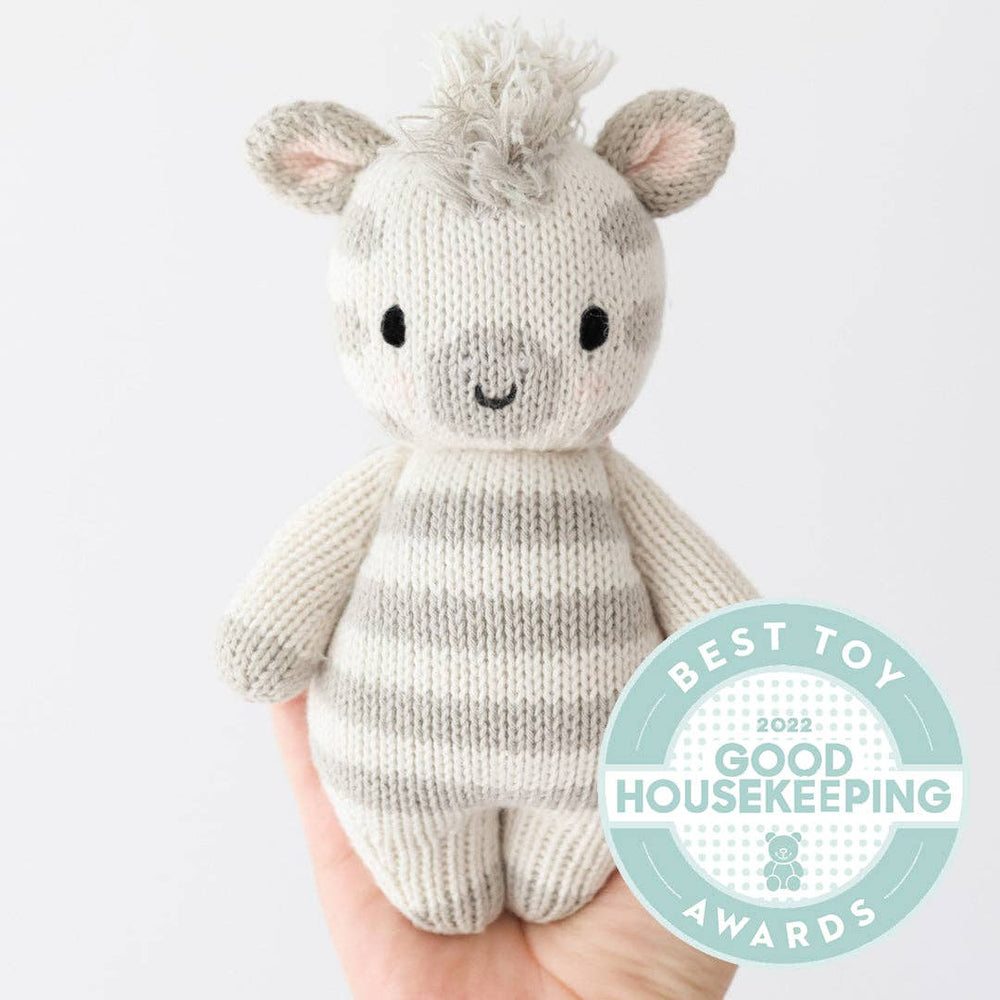 
                      
                        Hand holding 7-inch Cuddle + Kind Baby Zebra doll, size comparison for newborns and toddlers
                      
                    