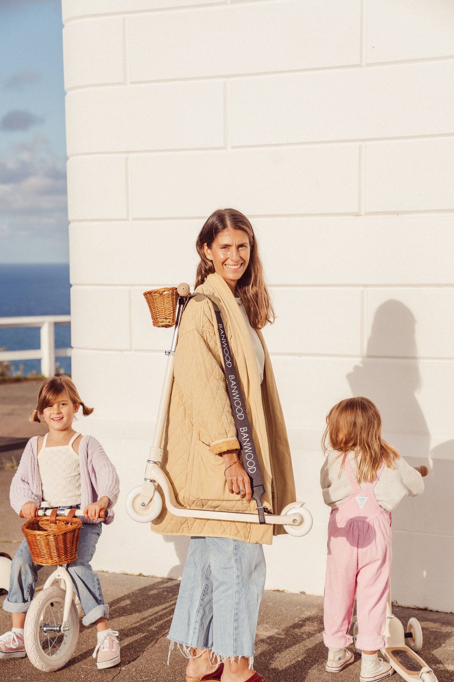 Parent carrying a Banwood scooter over shoulder using the Banwood Carry Strap in Black — Dacron strap with vegan leather ends and metal buckle