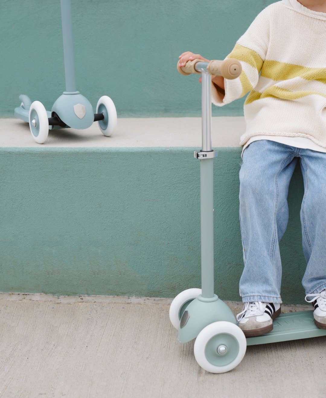 Child riding Banwood Eco Scooter in Clay — three-wheel recycled plastic scooter, outdoor setting