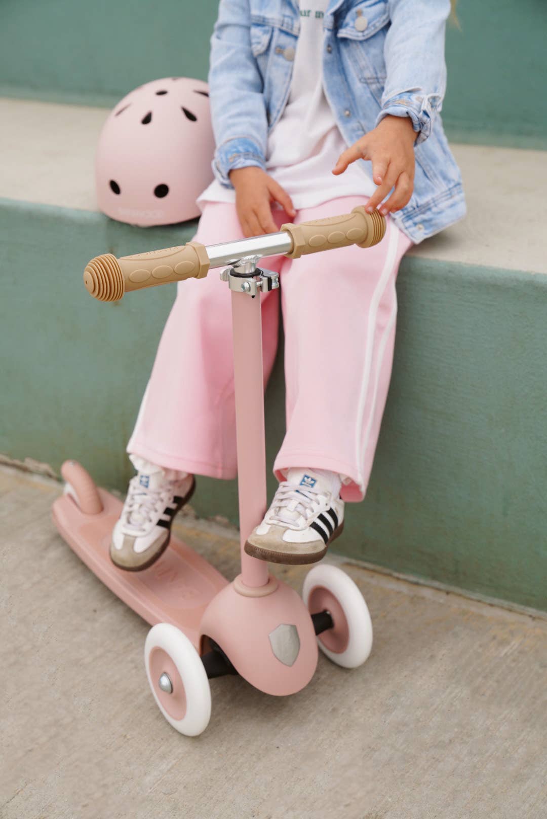 Child riding Banwood Eco Scooter in Dusty Rose — three-wheel recycled plastic scooter, outdoor setting