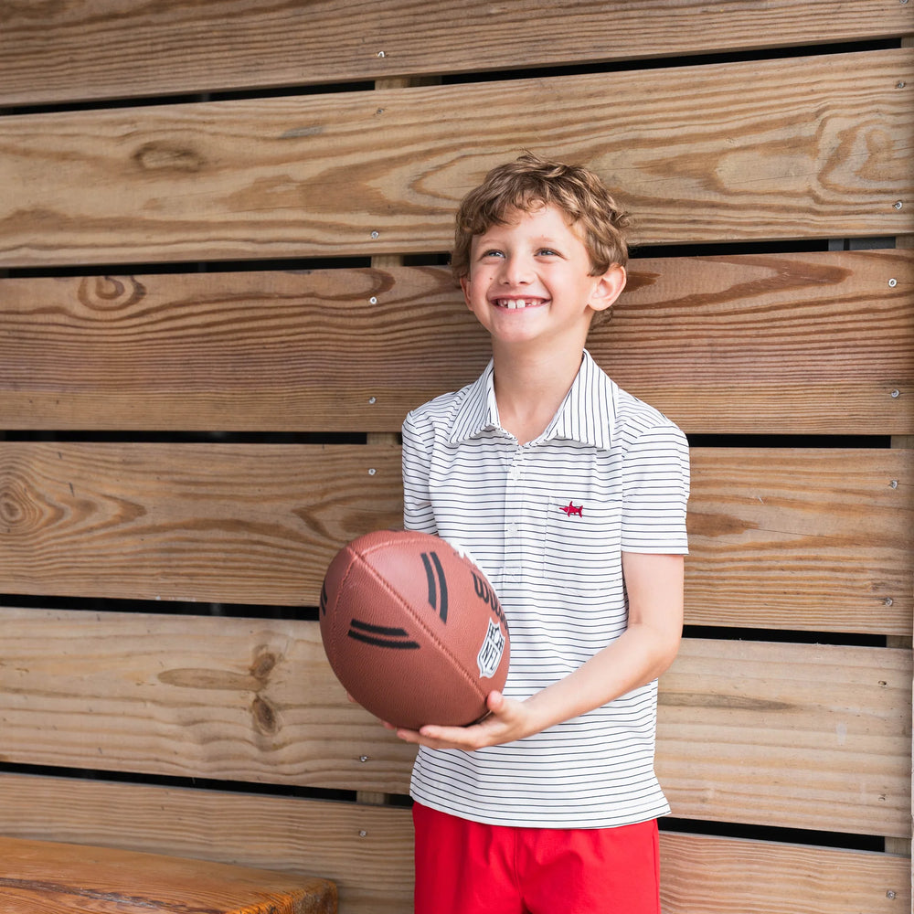 
                      
                        Young boy wearing Boys Marco Performance Polo paired with performance shorts, holding a football, showcasing soft, breathable, and durable play-ready style.
                      
                    