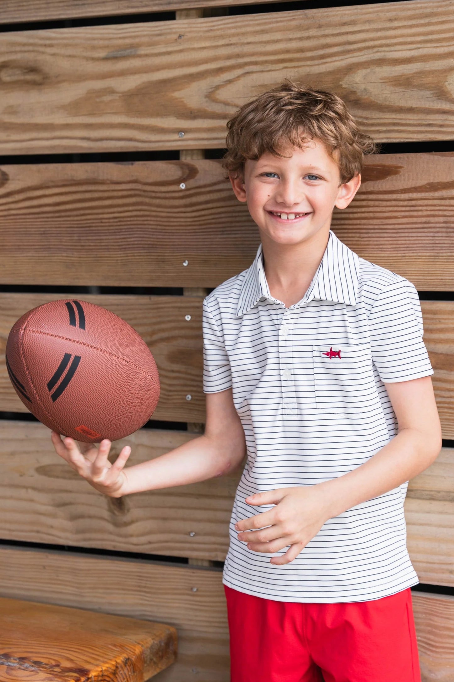 Boy in Boys Marco Performance Polo and performance shorts tossing a football, highlighting versatile, active-friendly, and stylish outfit for kids.