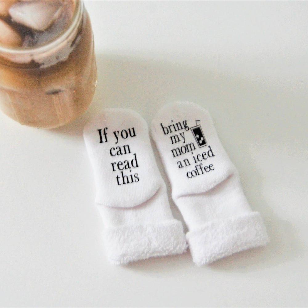 
                      
                        Adorable baby socks with iced coffee phrase hanging or on store display, ideal for gifting.
                      
                    