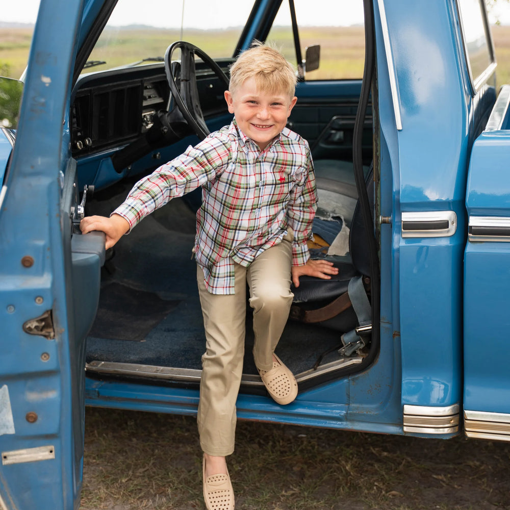 Boy in Carter Oxford Shirt climbing out of old truck, highlighting rugged, playful style and durable design.