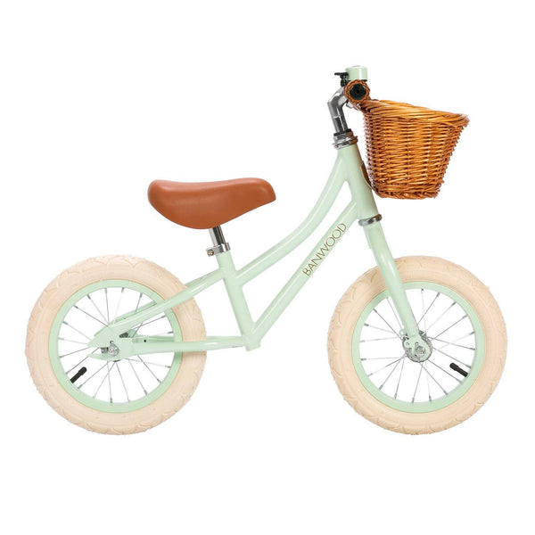 First Go Balance Bike in Pale Mint with beige tires, brown saddle, and a wicker front basket.