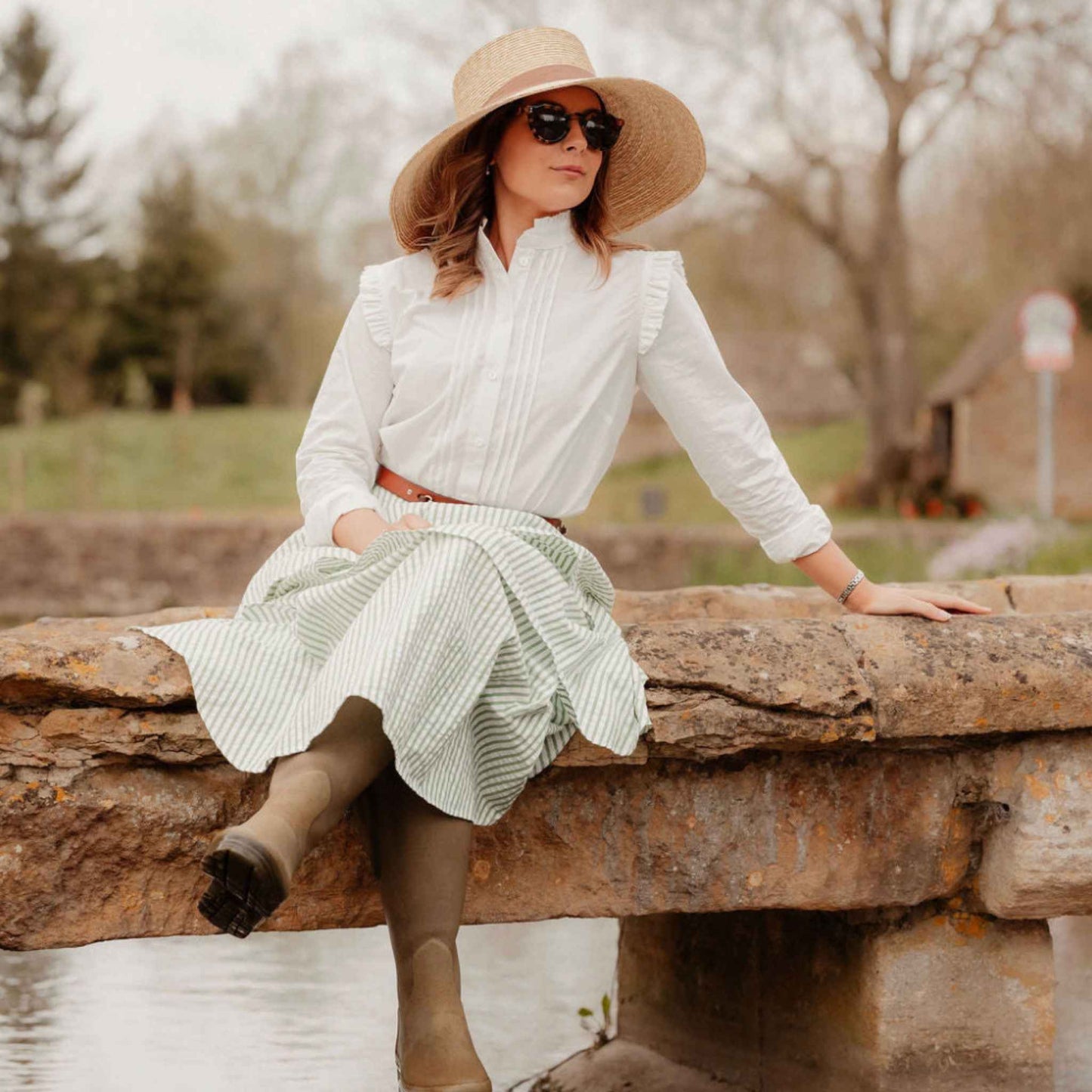 Lifestyle shot of model wearing blouse outdoors in field, showing elegant fit