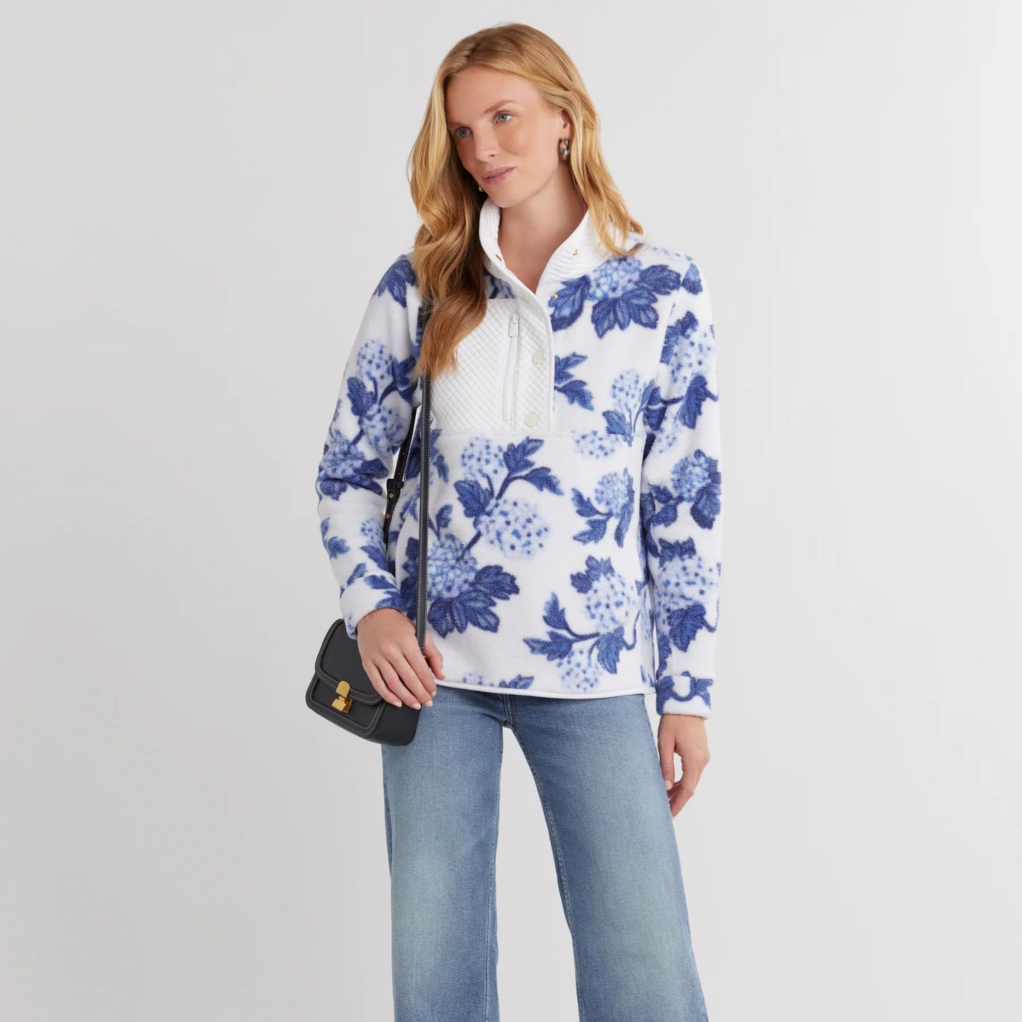 Model wearing Cherry Lawn Sherpa Fleece Pullover in hydrangea floral print, relaxed fit and chest zip pocket visible