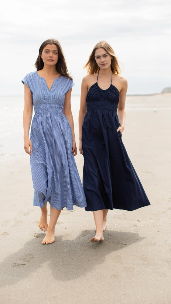 
                      
                        Two models strolling along the beach, featuring the Clara Dress in blue and white pinstripe paired with a navy Marea dress, capturing effortless summer style and friendship.
                      
                    