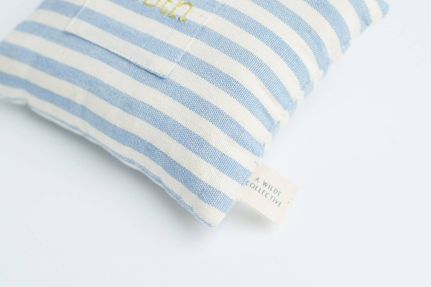 Close-up view showing the striped handwoven cotton fabric and small embroidered pocket of the tooth fairy pillow